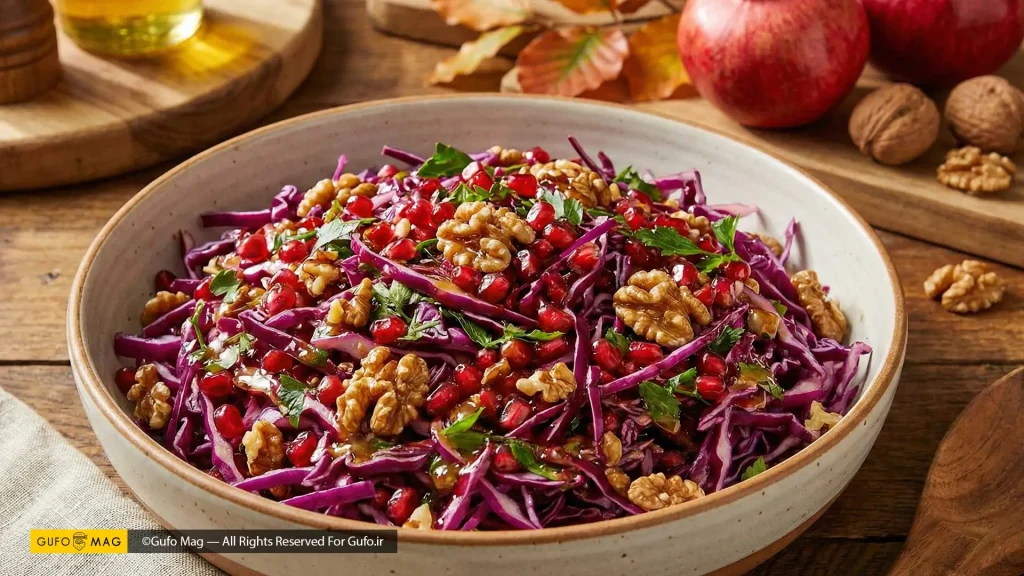 کاسه سالاد انار و کلم قرمز مجلسی با تزیین گردو و جعفری روی میز چوبی
