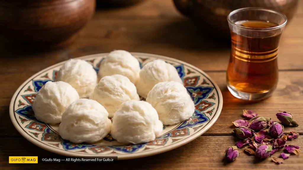 پشمک‌های لقمه‌ای توپی سرو شده در بشقاب سنتی کنار لیوان چای